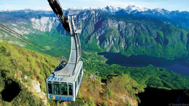 A cable car pulls up to the snow-covered top of Mount Vogel