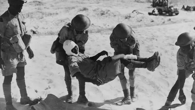 Les troupes coloniales françaises aident un soldat blessé sur une civière pendant la Seconde Guerre mondiale.