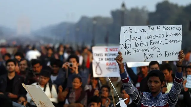 Многолюдная толпа, молодой мужчина с плакатом на переднем плане