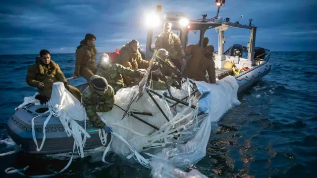 하얀색 물체를 배로 끌어 올리는 해군의 모습