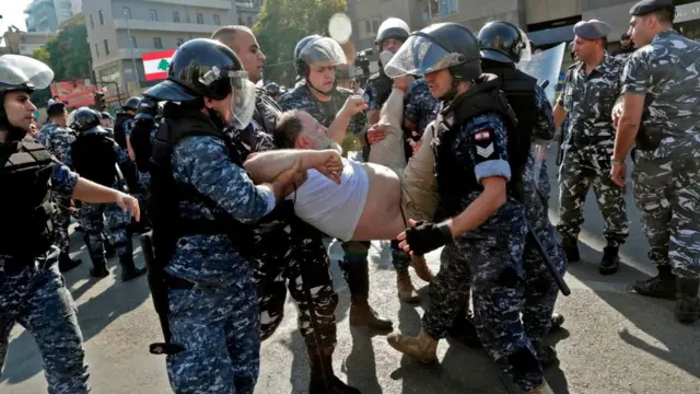 Polis, 31 Ekim 2019'da Beyrut'taki gösterilerde bir barikatı yıkan hükümet karşıtı protestocuları uzaklaştırırken.