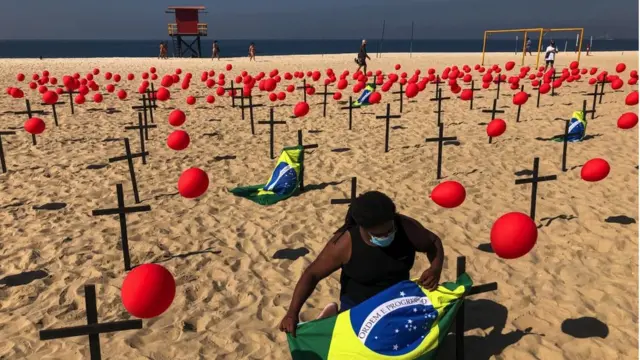 Un manifestant de l'ONG "Rio De Paz" attache un drapeau brésilien à une croix sur la plage de Copacabana, le 8 août 2020 à Rio de Janeiro, au Brésil.