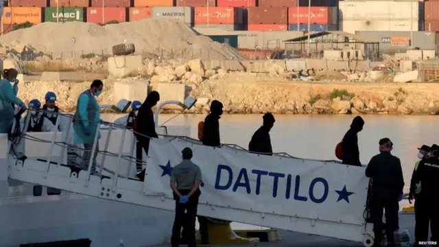 Migrants disembarking from Italian coast guard ship the Dattilo