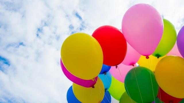 Colourful helium balloons over a cloudy sky