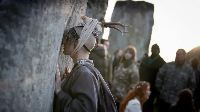 A woman holds one of the stones as druids, pagans and revellers gather at Stonehenge,