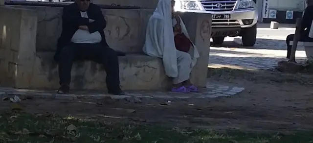 Un vieil homme en surpoids assis sur un banc public