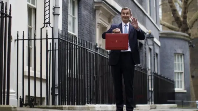 يلوّح وزير الخزانة البريطاني جيريمي هانت لعائلته وهو يقف مع حقيبة الميزانية