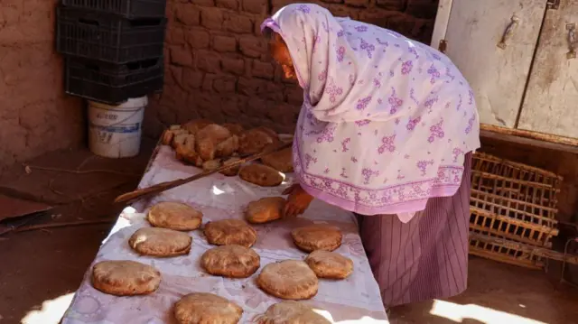 Local resident Naamat Jabal Sayyid Hasan, 75, bakes bread in a mud hut as she does daily to offer to people fleeing war-torn Sudan passing through in the northern town of Wadi Halfa