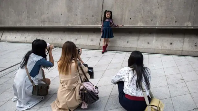 Three women photograph a little girl in South Korea