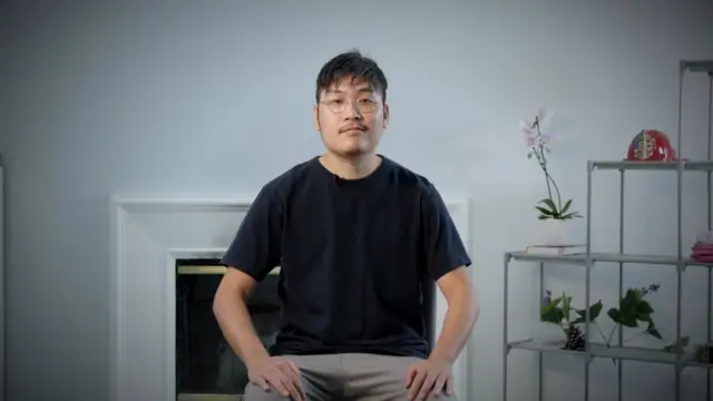 Liu Lipeng sits for a portrait photo with black tshirt and glasses on