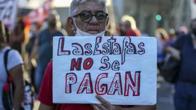 Un hombre con un cartel que dice: "Las estafas no se pagan"