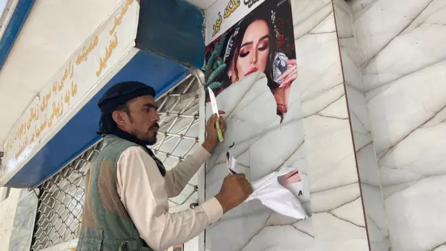 Pictures of an ad featuring a woman, being taken down in Kabul