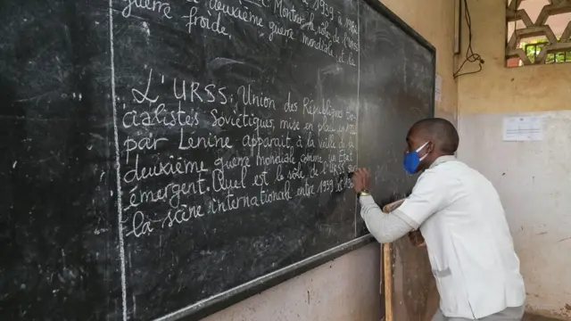 Un élève portant un masque facial comme mesure préventive contre la propagation du coronavirus COVID-19 écrit sur le tableau noir à Yaoundé, au Cameroun, le 1er juin 2020.