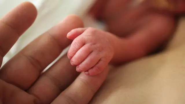 Un padre agarra la mano de su bebé