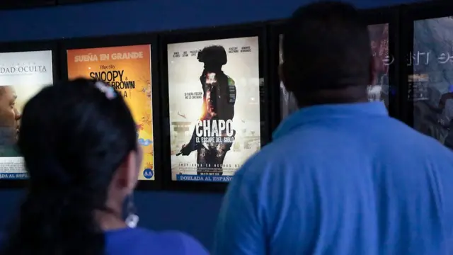 Una pareja frente a la cartelera de un cine de Acapulco, México.