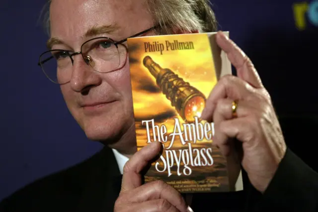 Philip Pullman con la portada de The Amber Spyglass