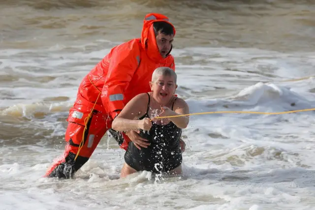 Spasilac pomaže vernici da izađe iz vode u mestu Saki na Krimu.