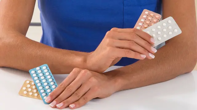 Manos de mujer con pastillas anticonceptivas.