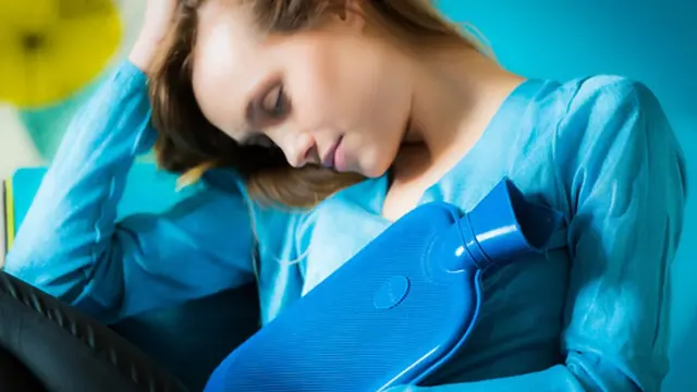 امرأة تحمل كيس ماء ساخن