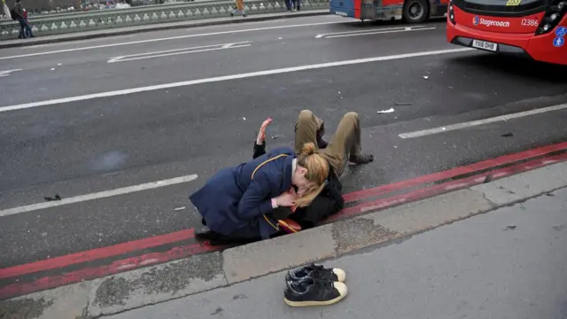 Женщина оказывает помощь пострадавшему на Вестминстерском мосту