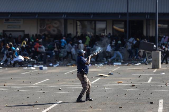 A member of the South African Police Services fires rubber bullets at rioters looting the Jabulani Mall in Soweto, southwest of Johannesburg, on 12 July 2021