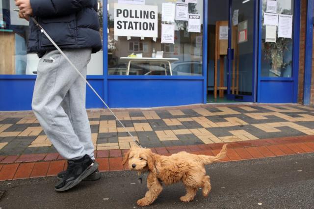 A man walks with a dog past a polling station in Oxford