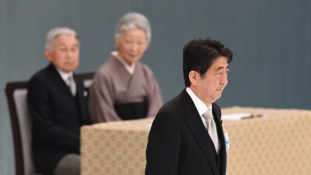 Japanese Prime Minister Shinzo Abe walks past Emperor Akihito and Empress Michiko during an annual memorial service for war victims, Tokyo, 2014