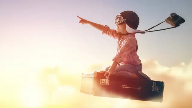 Una niña vuela sobre una maleta.