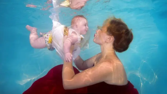 أم تلاعب طفلها تحت الماء