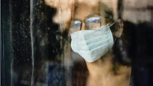 Woman looking through a wet window during lockdown because of Covid-19 - stock photo