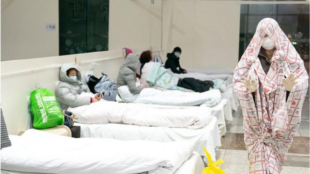 FEBRUARY 05 2020: A patient of 2019-nCoV, wrapped in a blanket, arrives at a large temporary hospital built two days ago in an exhibition center in Wuhan