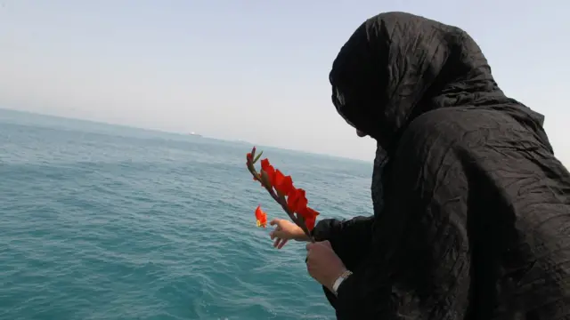 নিহত স্বজনের স্মরণে সাগরে ফুল দিচ্ছেন একজন ইরানী নারী