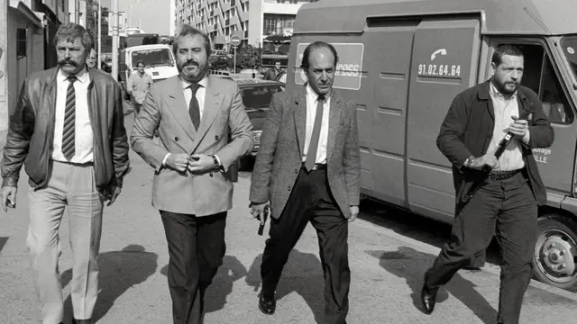 Yargıç Giovanni Falcone (soldan ikinci) 1986 yılında etrafında silahlı korumalarla gezerken. Falcone çok sayıda mafyayı tutuklayarak Riina'nın öfkesini kazanmıştı.