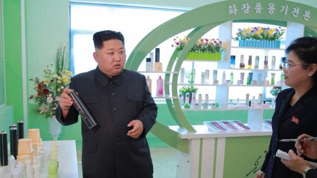金正恩在平壤化妝品廠內舉起一罐噴發膠（朝中社2017年10月28日發放照片）