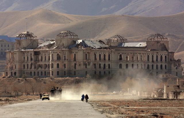 KABUL, AFGHANISTAN: Afghani people walk along a street in Kabul, with the ruined palace of former Afghani Prime Minister Hafizullo Amin in the background, 15 November 2001. Amin was killed in December 1979 in his palace by the officers of Soviet 'Alpha' special task unit, as a first action of Soviet 1979-1989 invasion to Afghanistan. The Northern Alliance opposition forces scored a crushing victory against Afghanistan's hardline Taliban regime 13 November evicting it from the capital Kabul and seizing control of a huge tract of surrounding territory.