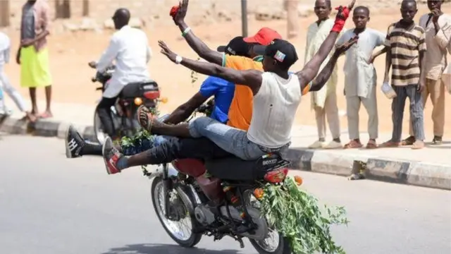 Three boys dey jubilate on top motorcycle