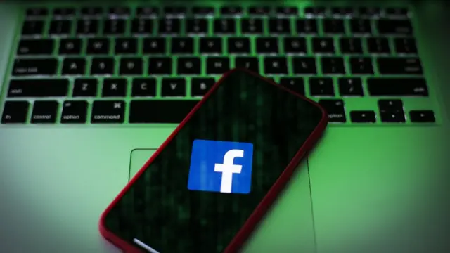 Ilustracija - logo Fejsbuka na ekranu telefona koji je postavljen na tastaturi