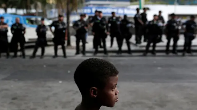 Menino com policiais ao fundo