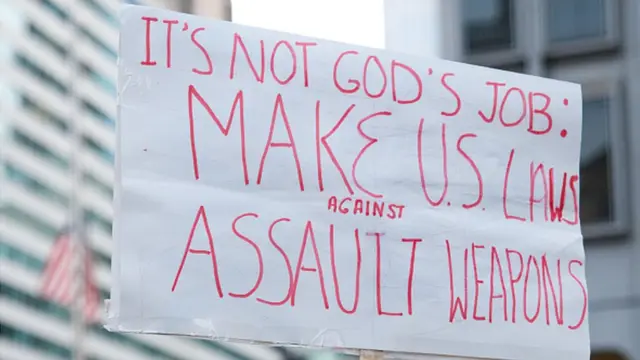 Pancarta en la que se puede leer: "No es tarea de Dios. Hagan leyes contra los fusiles de asalto"