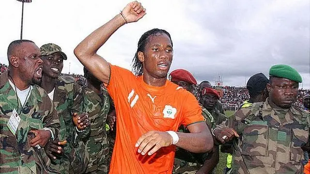 Drogba is escorted from the Bouake pitch by security personnel