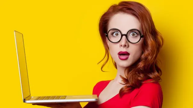 Mujer joven sosteniendo computadora.