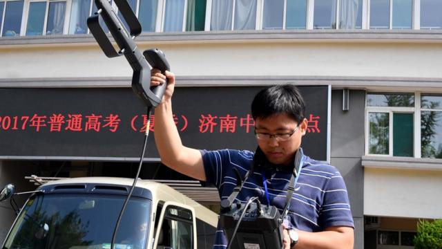 一名济南市无线电管理办公室的工作人员使用便携式电磁监测设备，对考点的电磁环境进行监测。