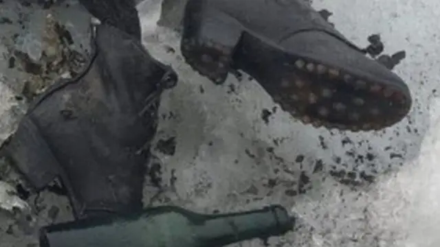 Les pieds d'un des corps avec une bouteille retrouvée à leur côté