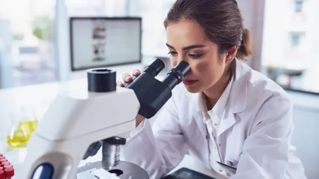 Científica observa en un microscopio.