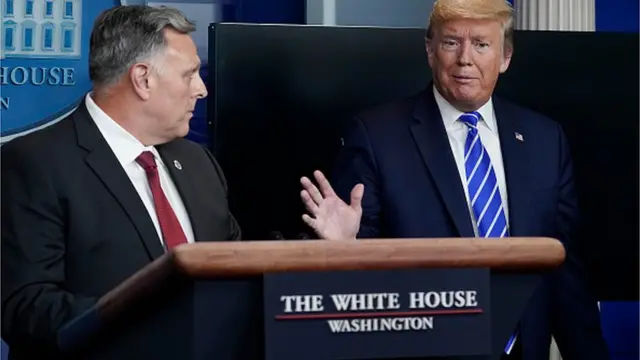 Трамп брифингде сүйлөп жаткан убагы, сол жагында Уильям Брайан