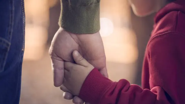 Pai segura mão de filho