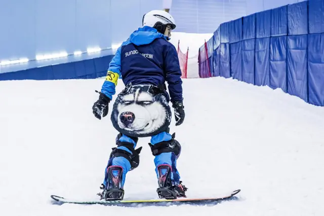 A snowboarder with a wolf on his outfit