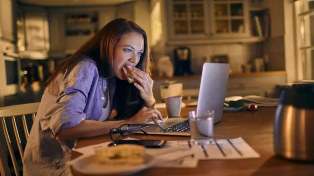 Mulher comendo na frente do computador