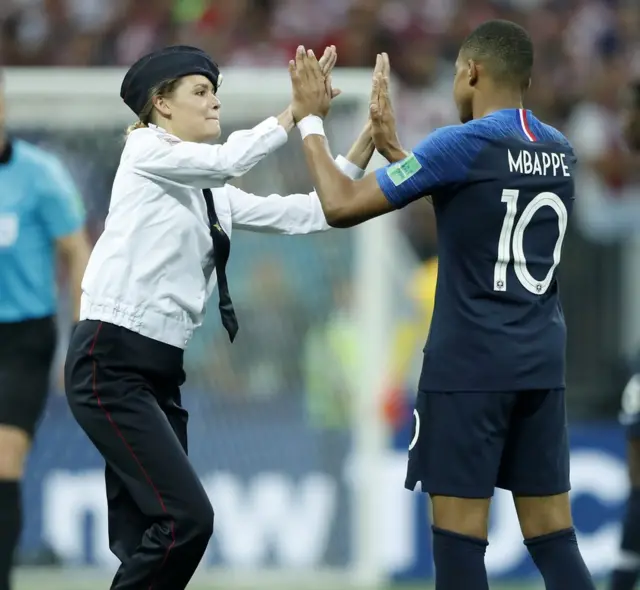 Una de las "intrusas" que accedió al campo de fútbol en la final de Rusia 2018 saluda a Mbappé.