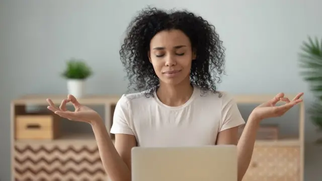 Mulher meditando enquanto trabalha no computador